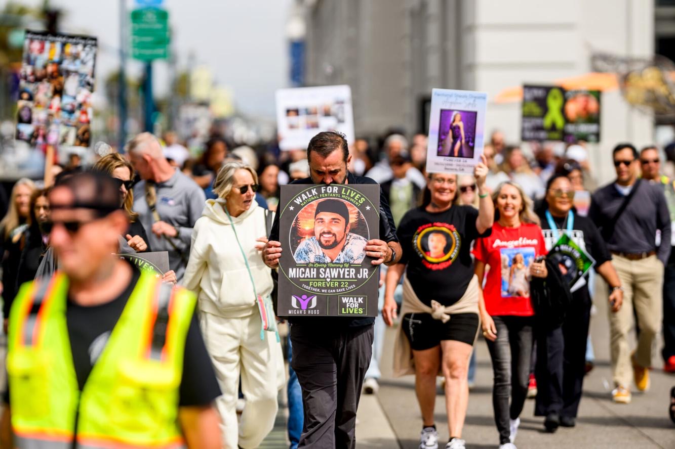 A walker carries a memorial sign for Micah Sawyer Jr., Forever 22, at Walk for Lives 2026